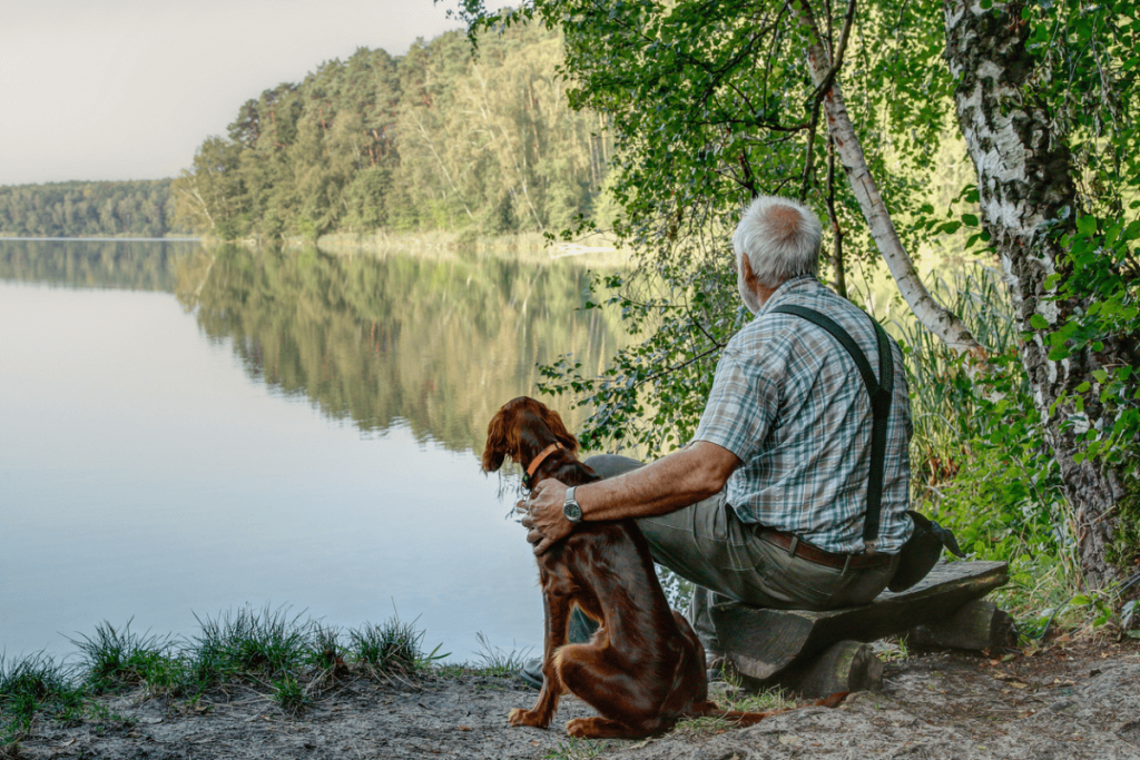 Mann schaut mit seinem Hund auf einen See